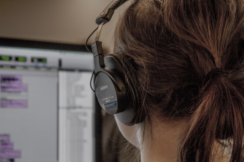 picture of woman at computer with headphones on